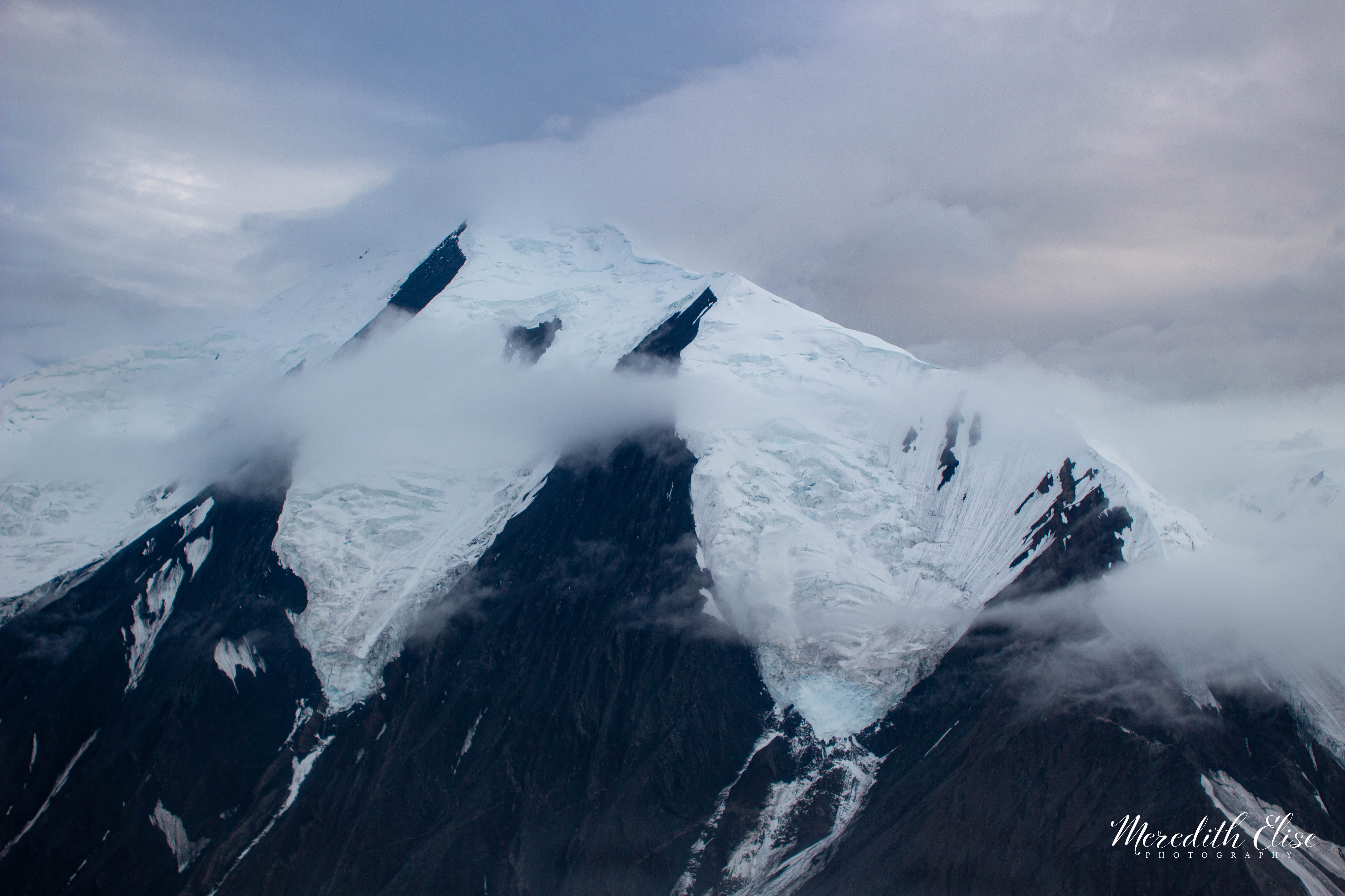 Snow-capped glaciated peaks wrapped in low cloud