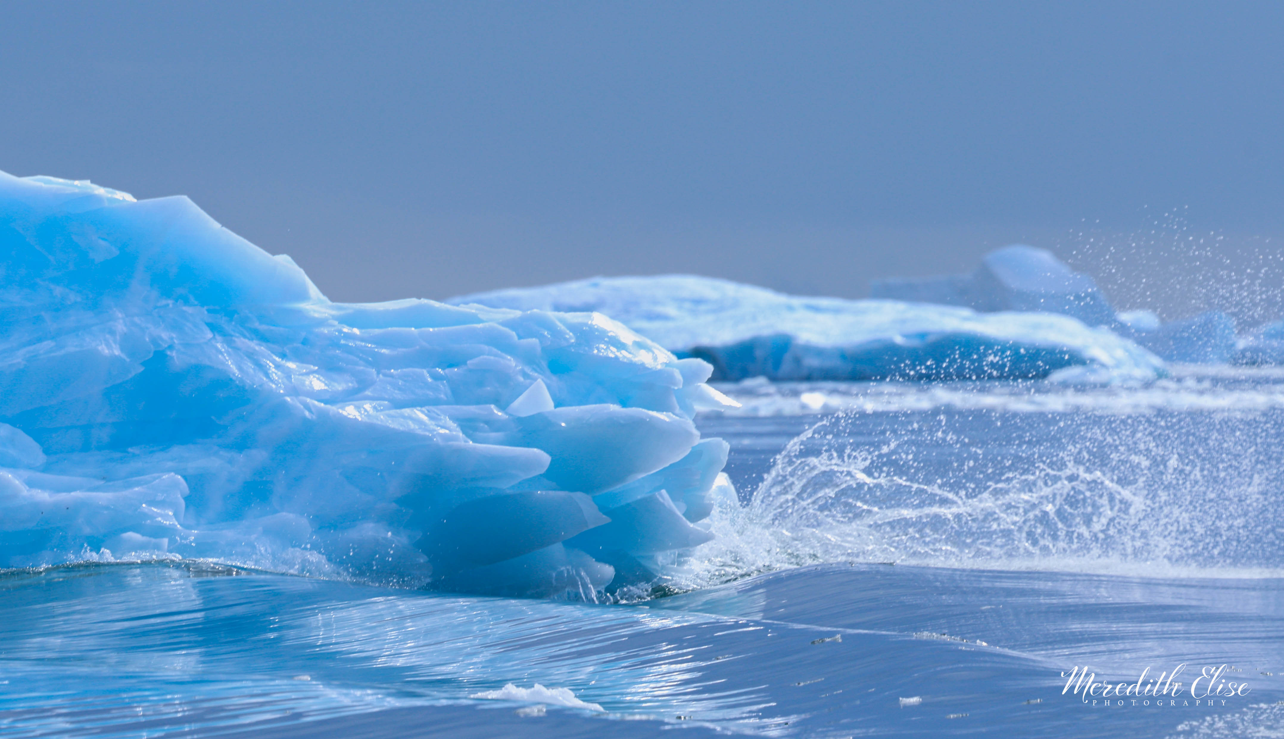 Vivid blue glacial ice chunks tumbling through polar waves