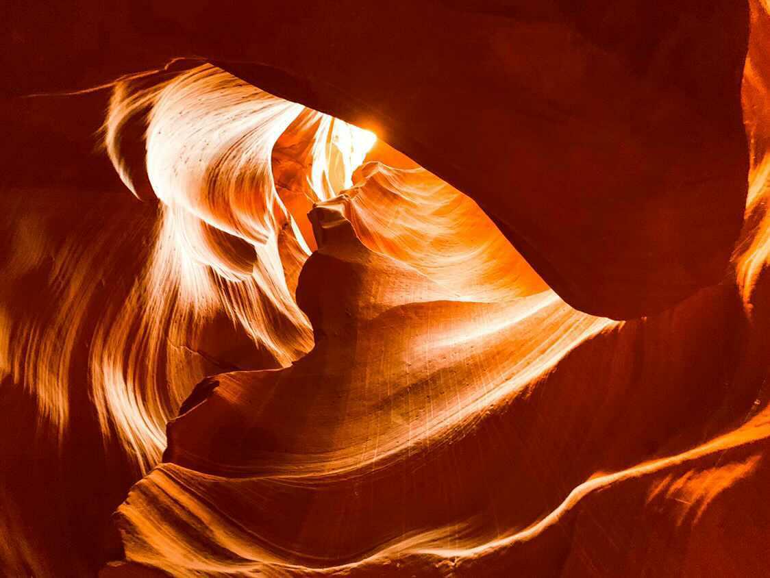 Light beam piercing glowing amber walls of Antelope Canyon