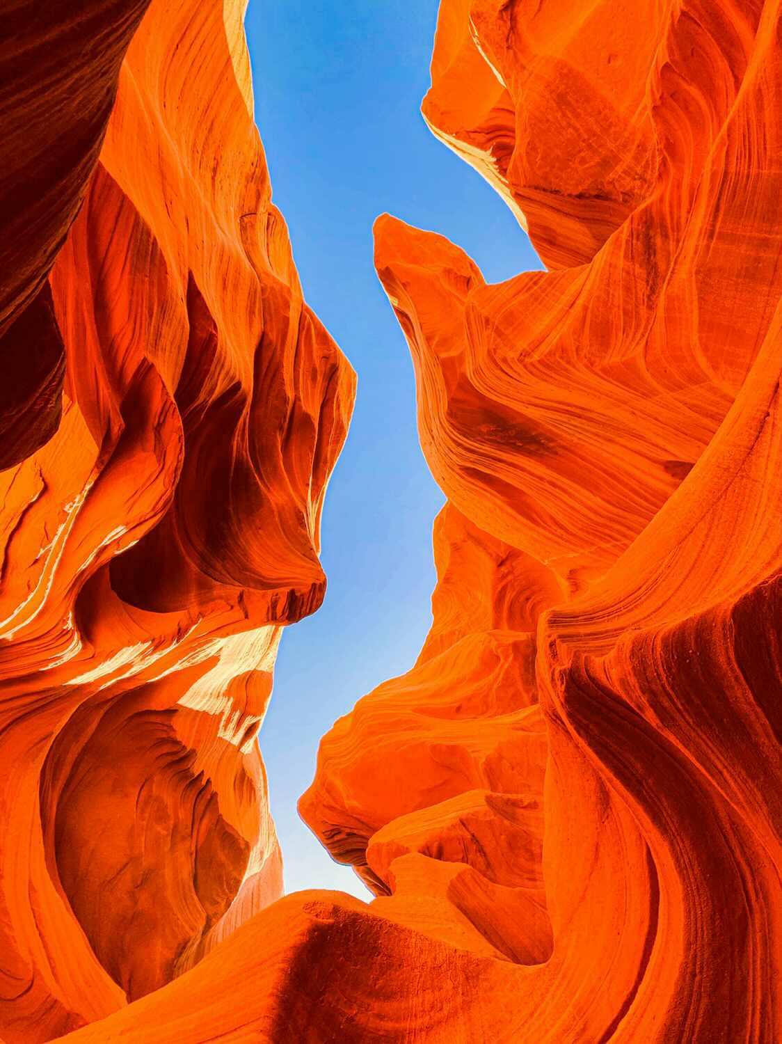 Looking up through sculpted sandstone to a sliver of blue sky