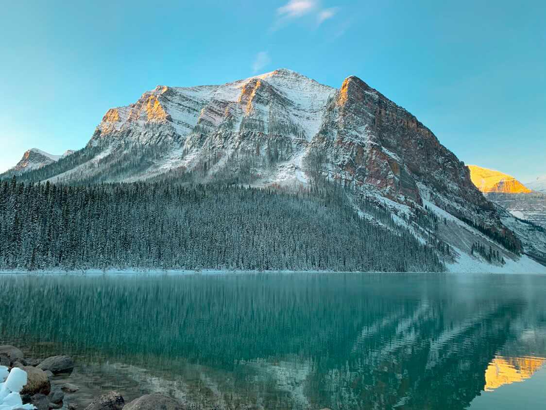 Lake Louise at dawn, reflecting snow-dusted peaks in turquoise water