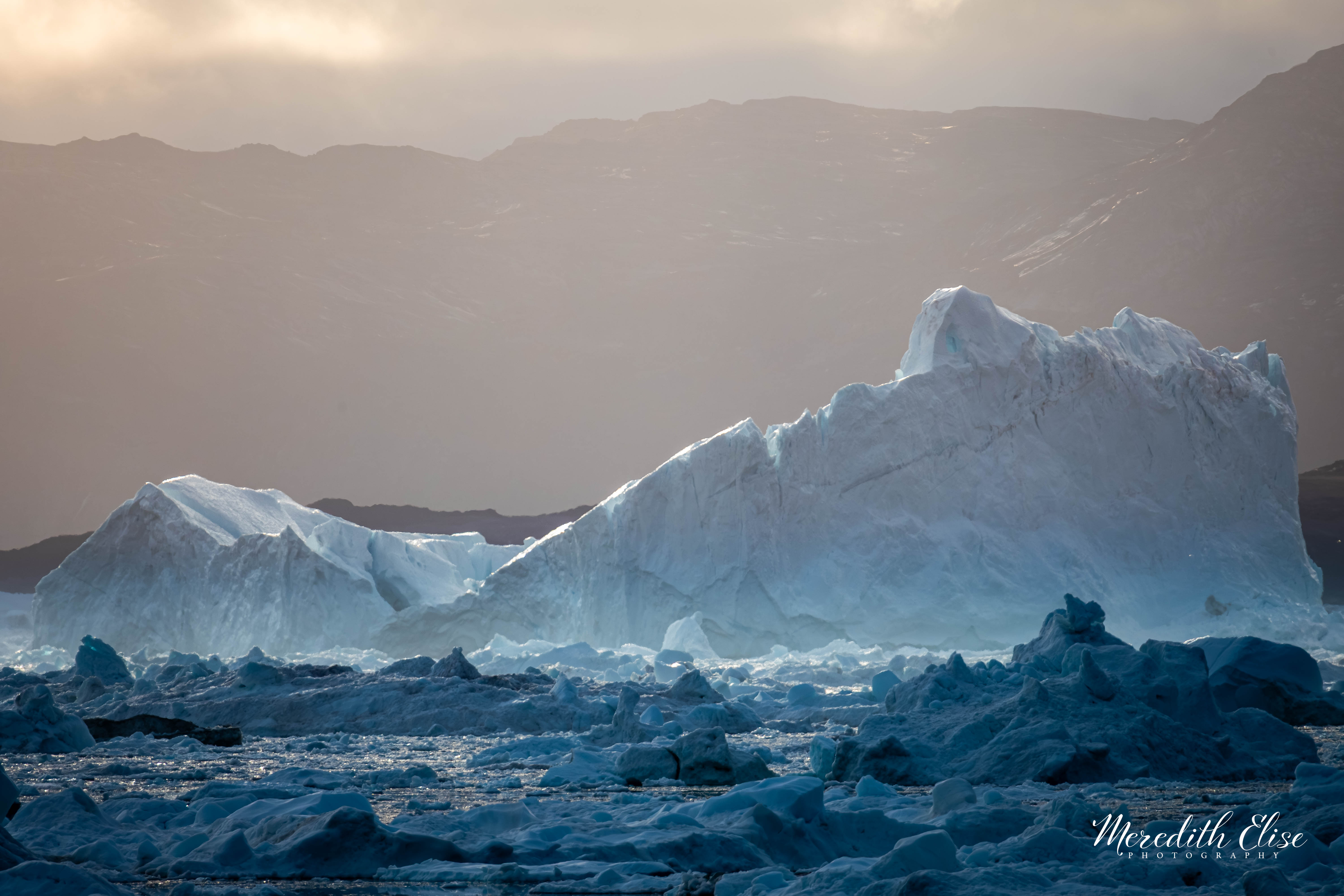 A massive iceberg catching warm light in a field of Arctic sea ice