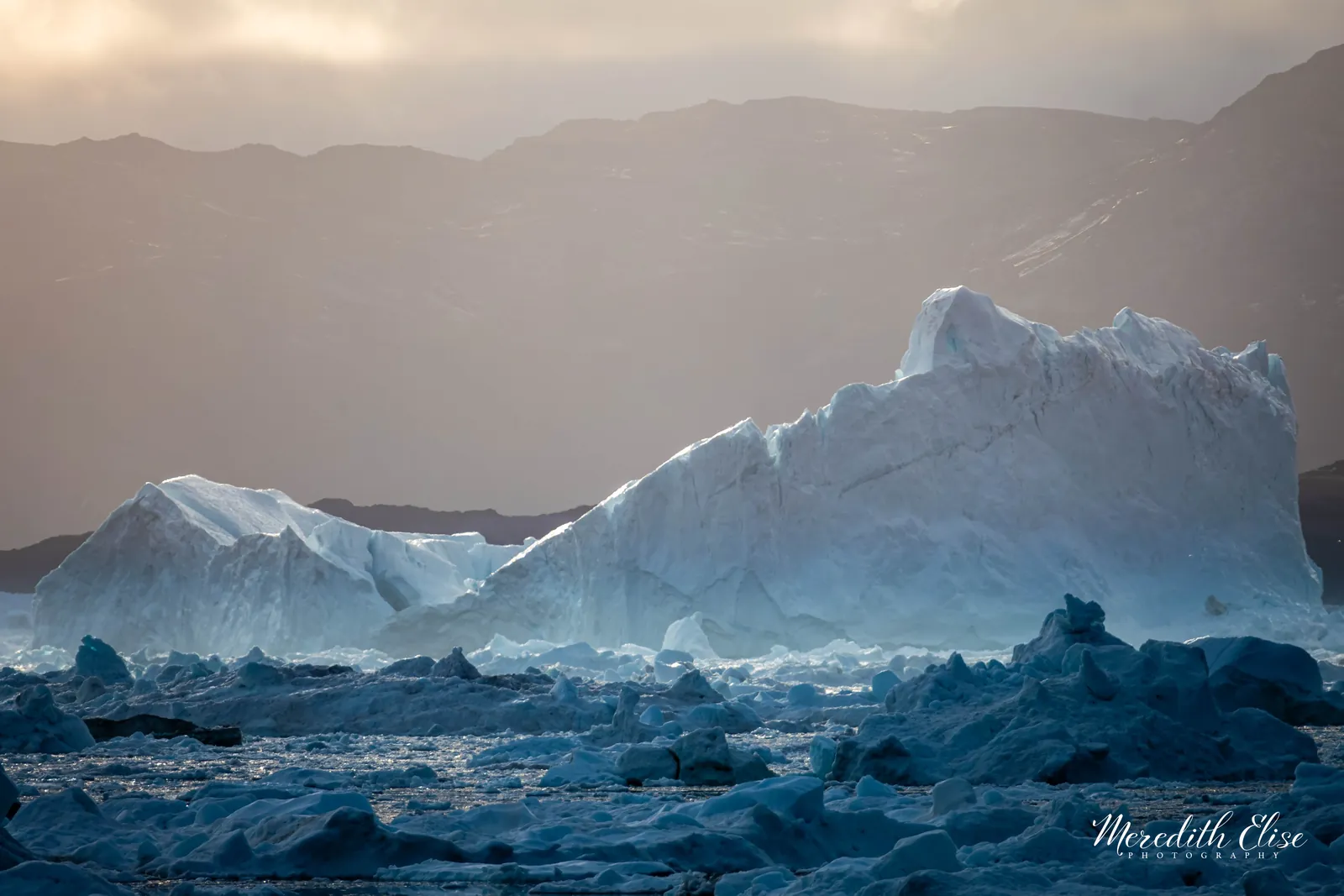 Massive iceberg catching warm dusk light in a field of Arctic sea ice — fine art print